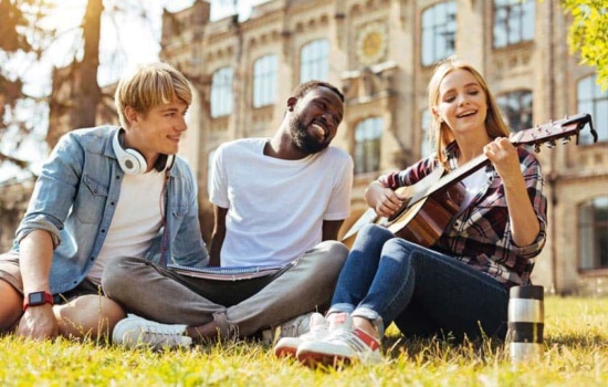 Music students playing guitar on the grounds of college campus